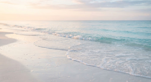 Small waves arriving one after another on a pale shore at sunrise
